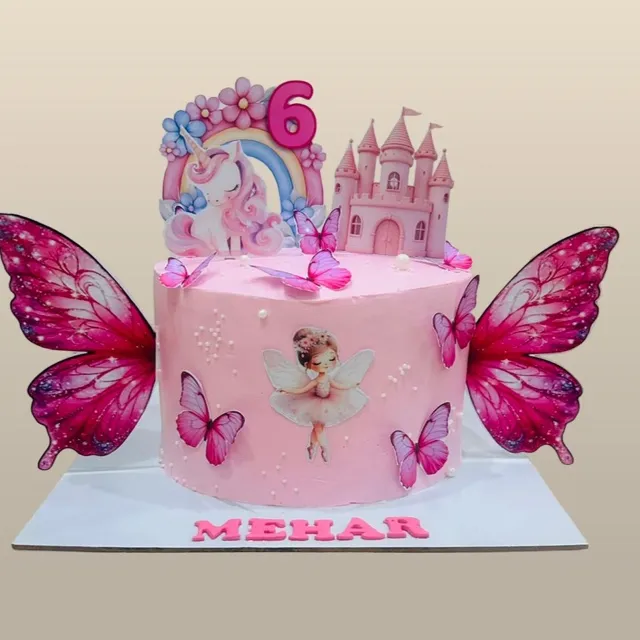 A Fairy-Tale Birthday Cake for Mehar — A pink butterfly-wing cake with a fairy, unicorn, and castle topper, finished with a hand-lettered name plaque.