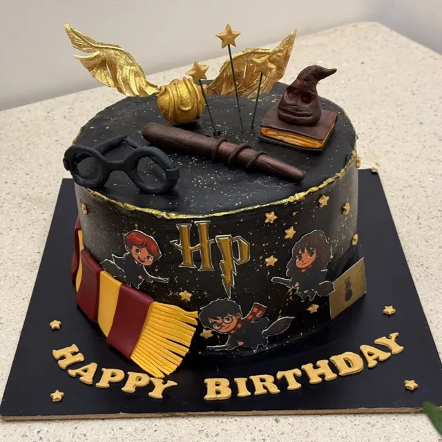 A Harry Potter Birthday Cake — A Harry Potter-themed cake with a hand-sculpted golden snitch, sorting hat, wand, and house scarf, finished with gold lettering.